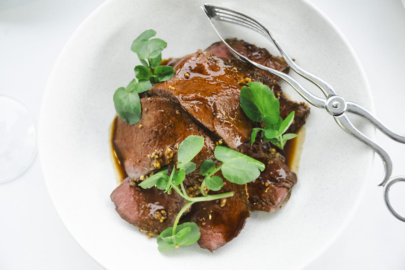 A close up of a beef dish garnished with greenery