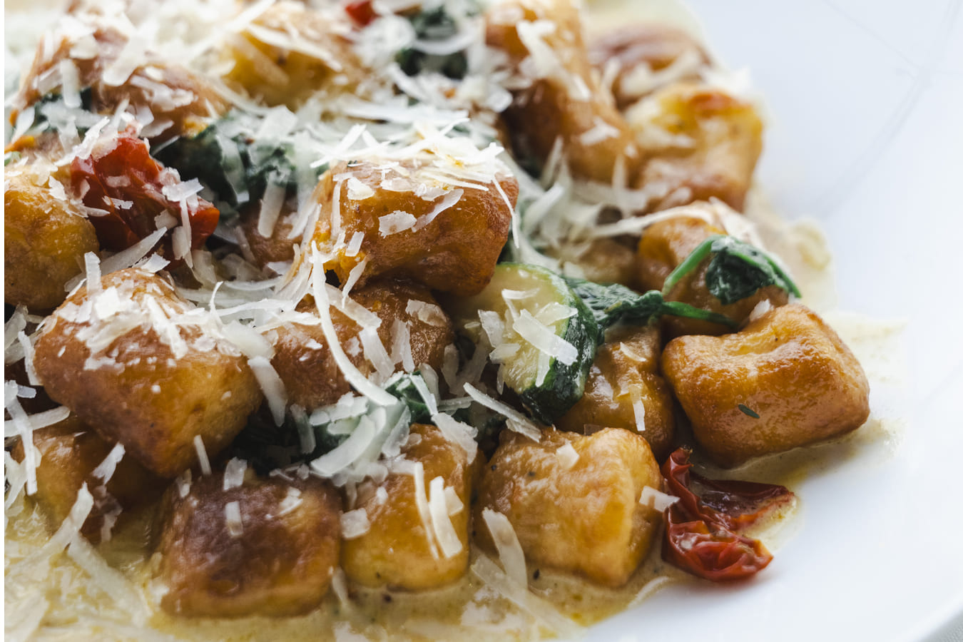 A close up of a pasta dish containing vegetables and topped with cheese